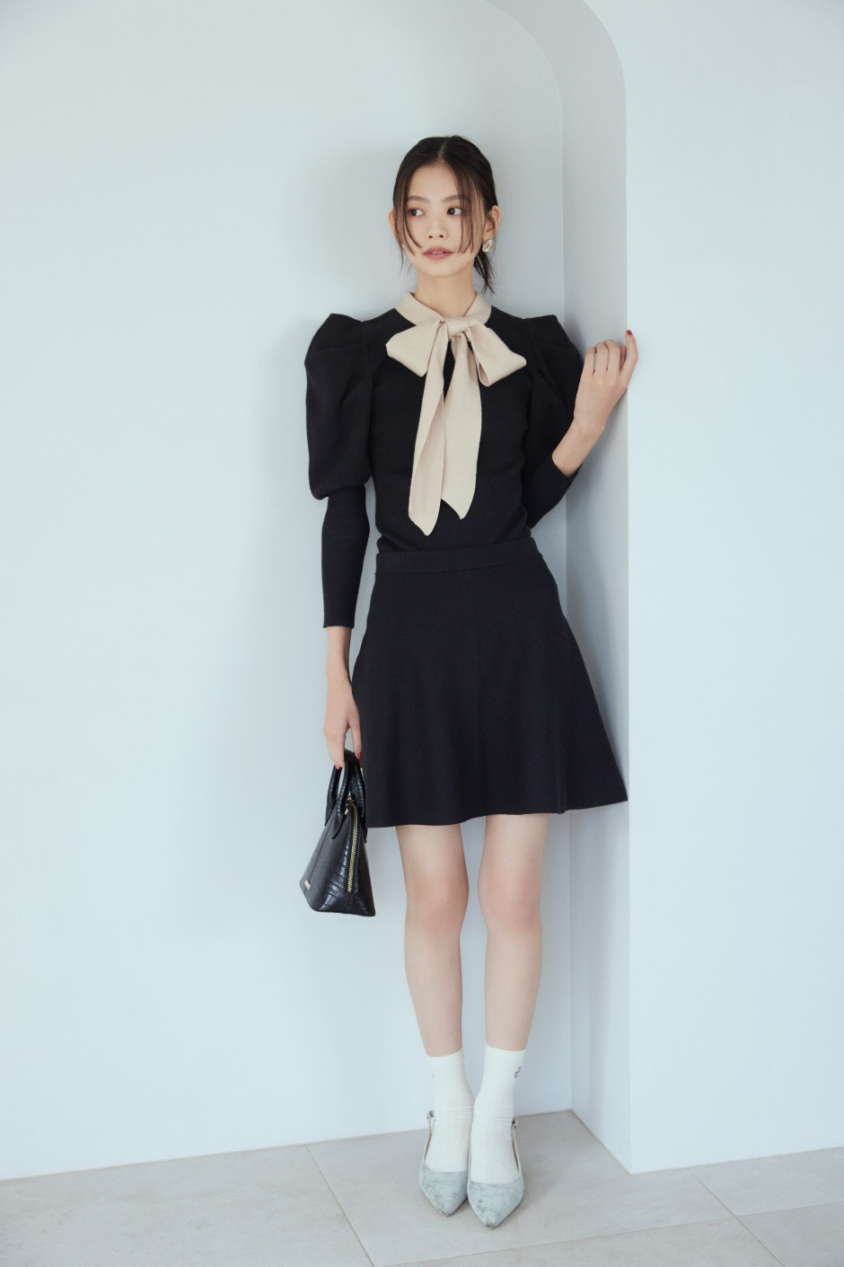 黒のセットアップを着た壁に寄りかかっている女性