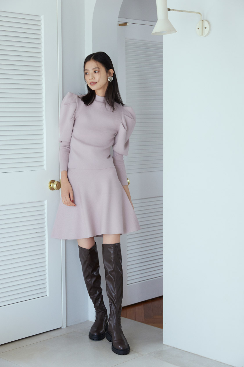 ピンクのニットセットアップ・ブラウンのロングブーツを履いた女性