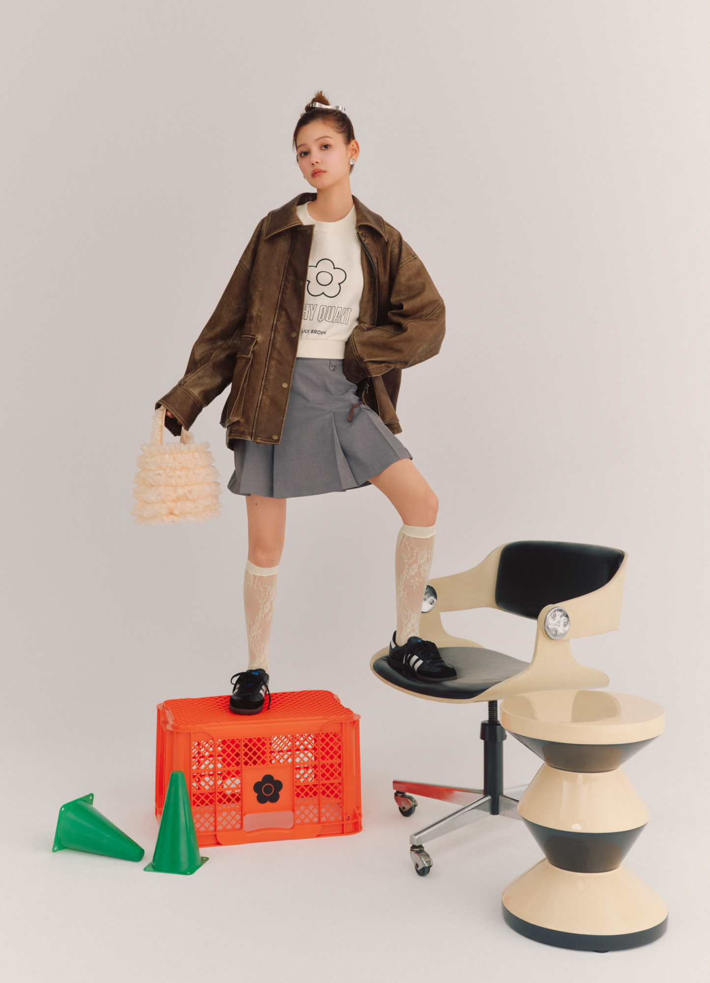 バリエーションドロストオーバージャケット・【LILY BROWN×MARY QUANT】デイジークロップドスウェット・ベルト付きタックプリーツスカショーパン・シアーレースハイソックス・チュールバケットバッグ・リボンバレッタセット・ハートイヤリングを着用した女性