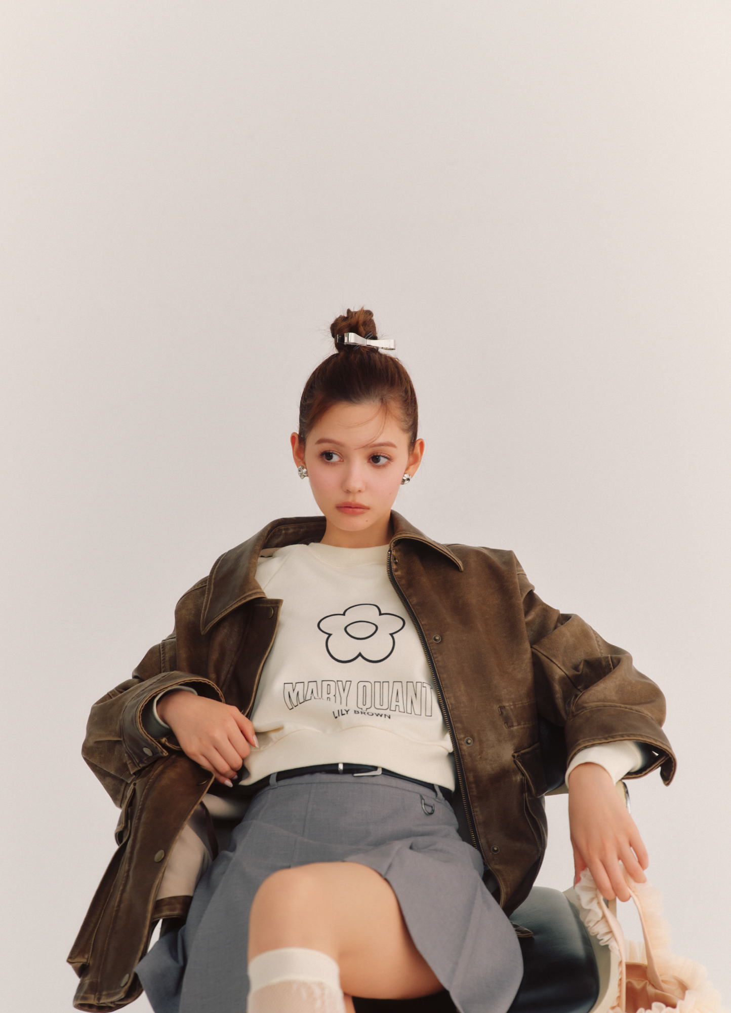 バリエーションドロストオーバージャケット・【LILY BROWN×MARY QUANT】デイジークロップドスウェット・ベルト付きタックプリーツスカショーパン・シアーレースハイソックス・チュールバケットバッグ・リボンバレッタセット・ハートイヤリングを着用した女性