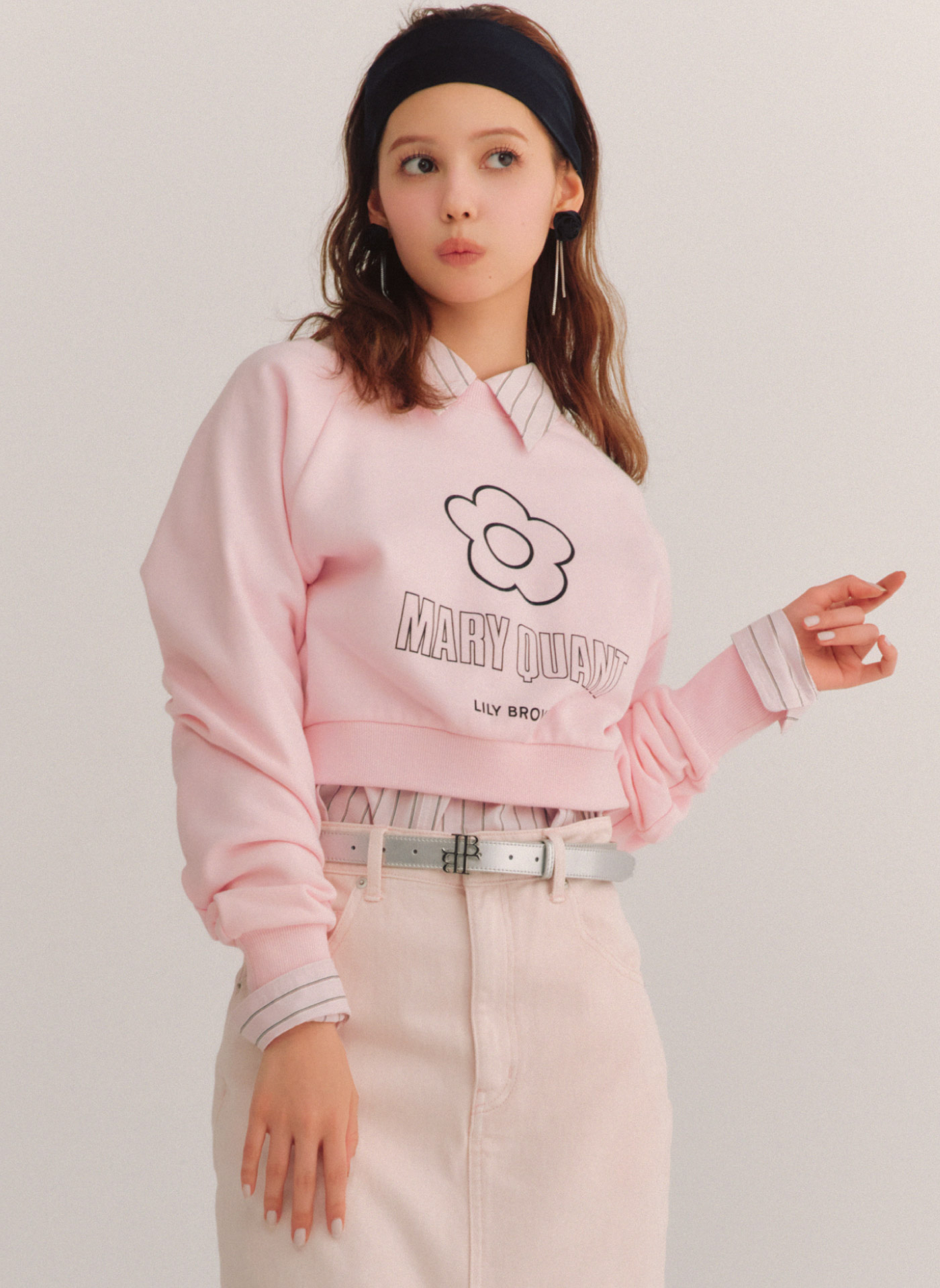【LILY BROWN×MARY QUANT】デイジークロップドスウェット・Lily Bearロングシャツ・ストレートデニムスカート・バックルブーツ・ロゴバックルベルト・ローズモチーフピアスを着用した女性