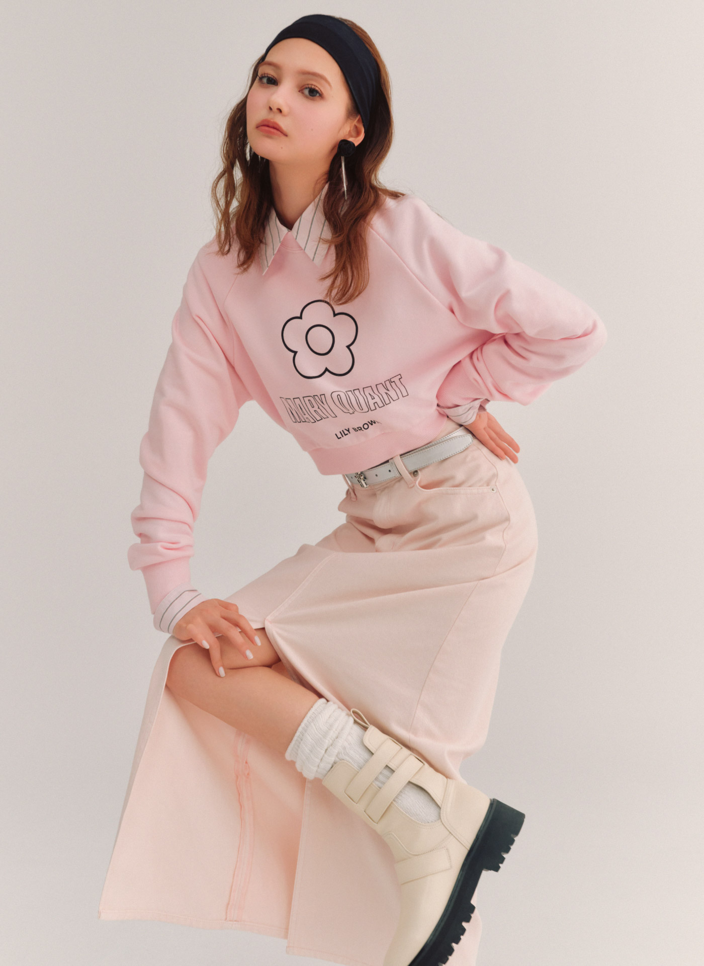 【LILY BROWN×MARY QUANT】デイジークロップドスウェット・Lily Bearロングシャツ・ストレートデニムスカート・バックルブーツ・ロゴバックルベルト・ローズモチーフピアスを着用した女性