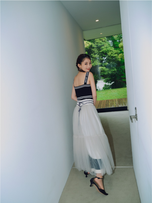 【LILY BROWN×MARY QUANT】ニットキャミワンピース・ダブルラインチュールスカート・【LILY BROWN×MARY QUANT】シアーオーバーシャツ・サテンストラップパンプス・【LILY BROWN×MARY QUANT】デイジークリアイヤリング・リボンディティールミュール・【LILY BROWN×MARY QUANT】デイジークリアリングを着用した女性