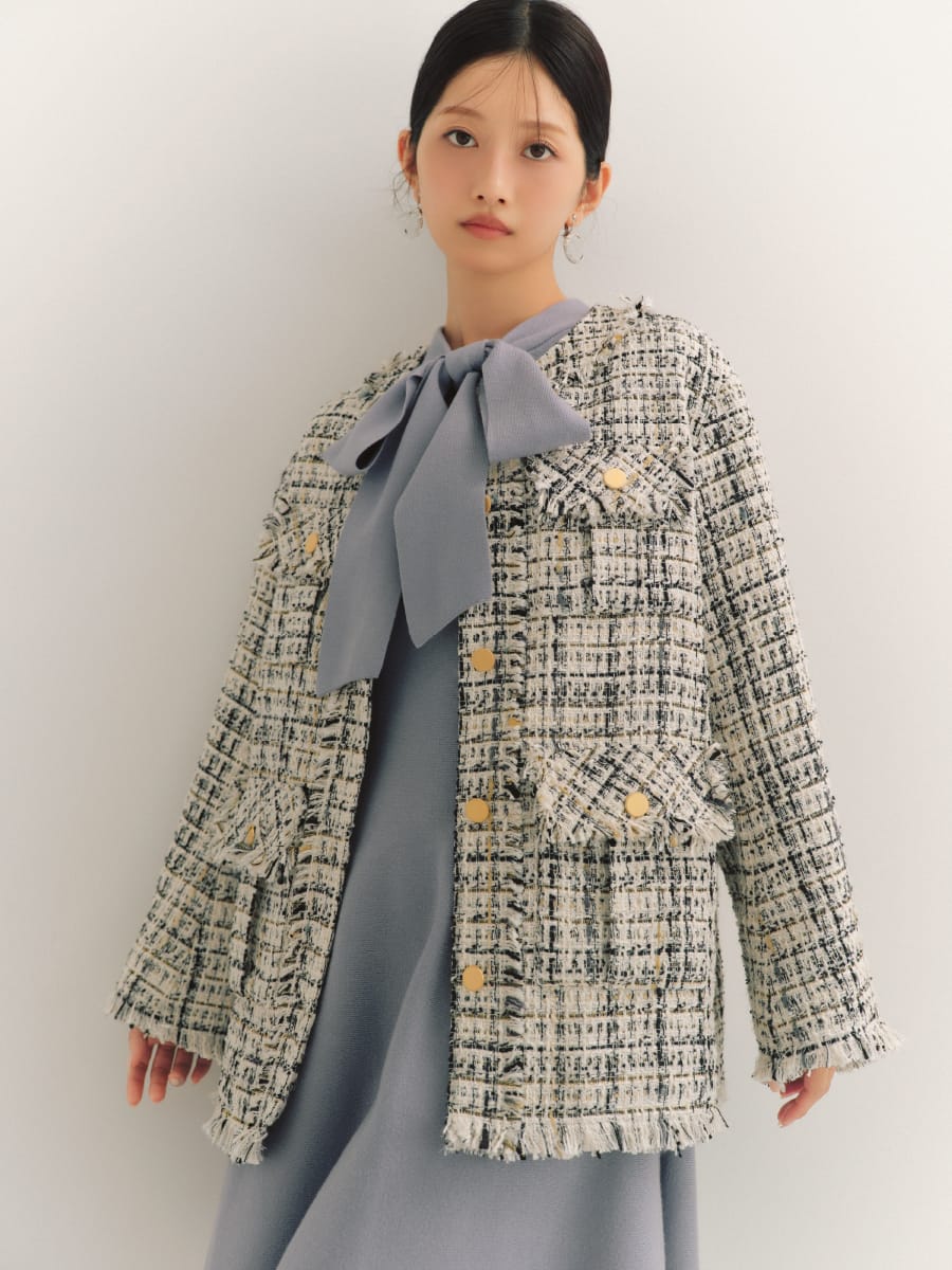 フリンジツイードノーカラージャケット&ボウタイニットミニワンピースを着た女性