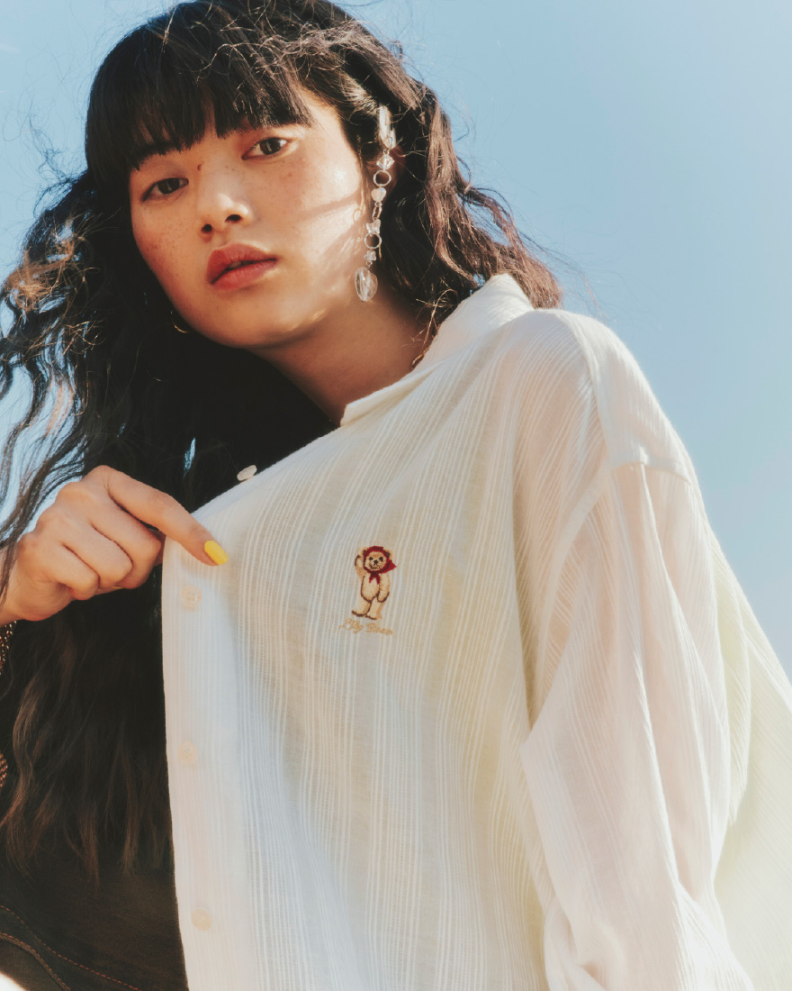 Lily Bearシアーオーバーシャツ・Lilyロゴ刺繍カップインキャミソール・ルーズフィットワイドデニムパンツ・ビジューミニショルダーバッグ・ビジュー付きスニーカーソールサンダル・カラーストーンピアス・バリエーションスリーピン・ハートストーンカラーバリエーションネックレス・2WAYチェーンチャームネックレス・ヴィンテージハートリングを着用した女性