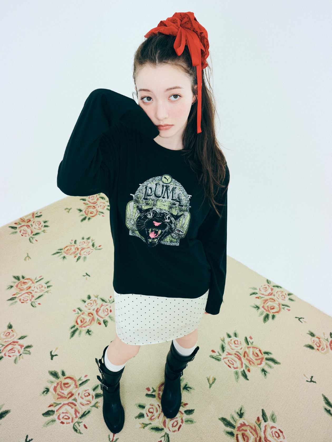 ロングTシャツ、スカート、ヘアアクセサリー、ピアス、ブーツを着用した女性