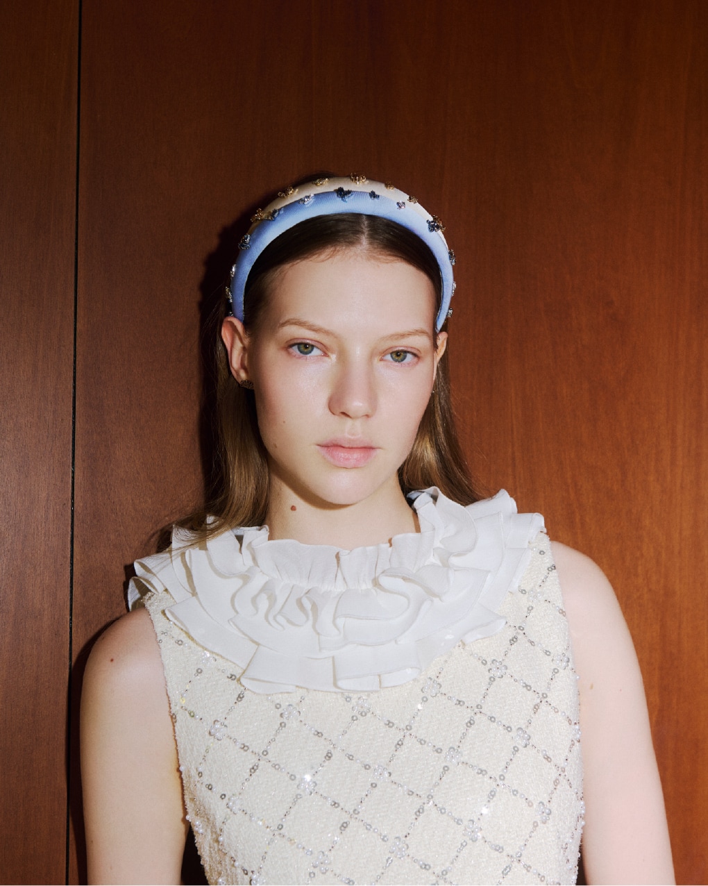 ビジューが全面に施されたアイボリーの2wayミニワンピースにブルーのビジューカチューシャを着用した女性のバストアップ写真