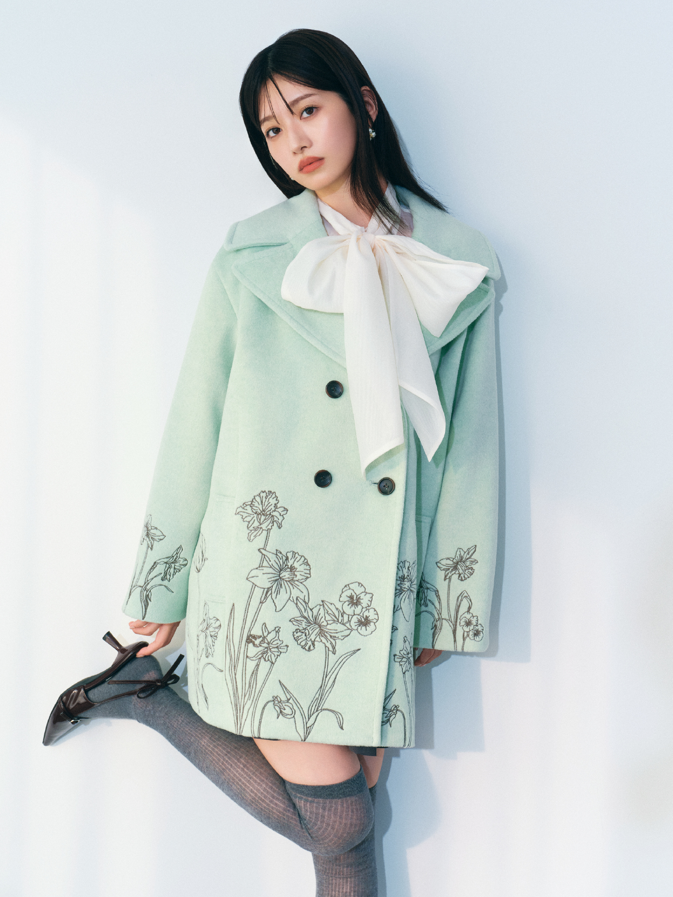 ミントのエンブロイダリーコクーンコート・アイボリーのビックボウタイブラウス・グレーのベルト付きプリーツスカショーパンとシアーコットンニーハイソックス・ブラウンのリボンスリングバックパンプス・LBロゴパールピアスの着用例