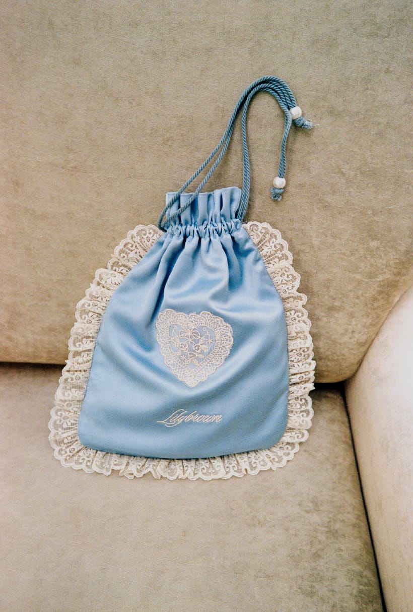 love クラシックミドルトレンチコート＆Lily Bearレターモチーフバリエシャツ＆２wayボリュームシャツスカート＆2wayバックパック＆ウッドソールスタッズサボを着用した女性