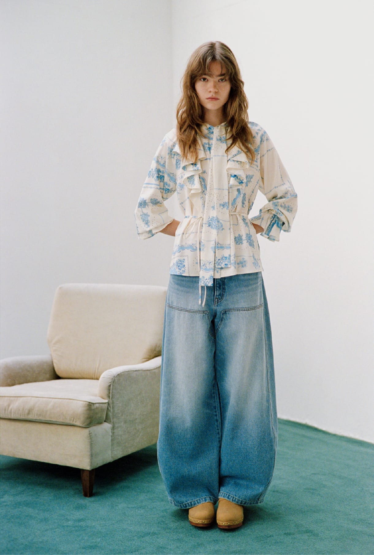 スカーフプリントボウタイブラウス＆ダブルニーカーブワイドデニムパンツ＆ウッドソールスタッズサボを着用した女性