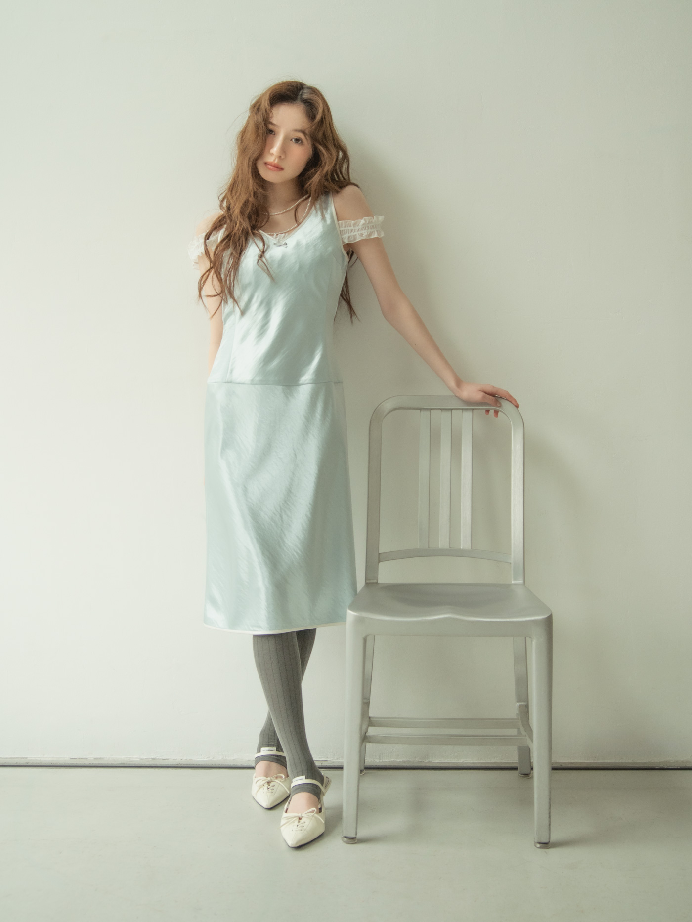 ミントグリーンのキャミソールドレスを着て椅子に手をかけるモデル