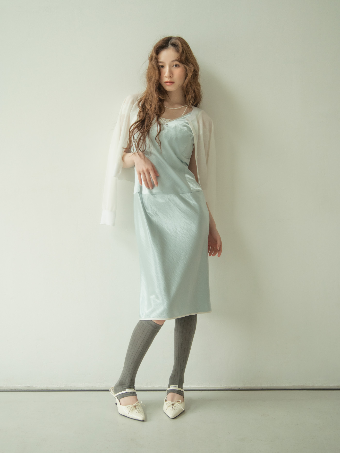 ミントグリーンのキャミソールドレスを着て椅子に手をかけるモデル