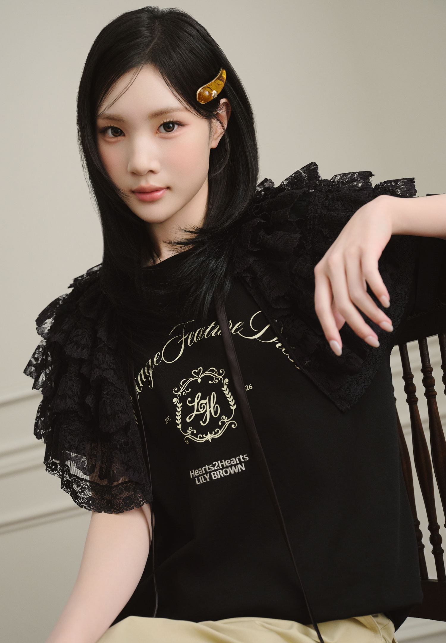 黒いフリルトップスを着用し、黄色いヘアクリップをつけた女性モデルの上半身カット