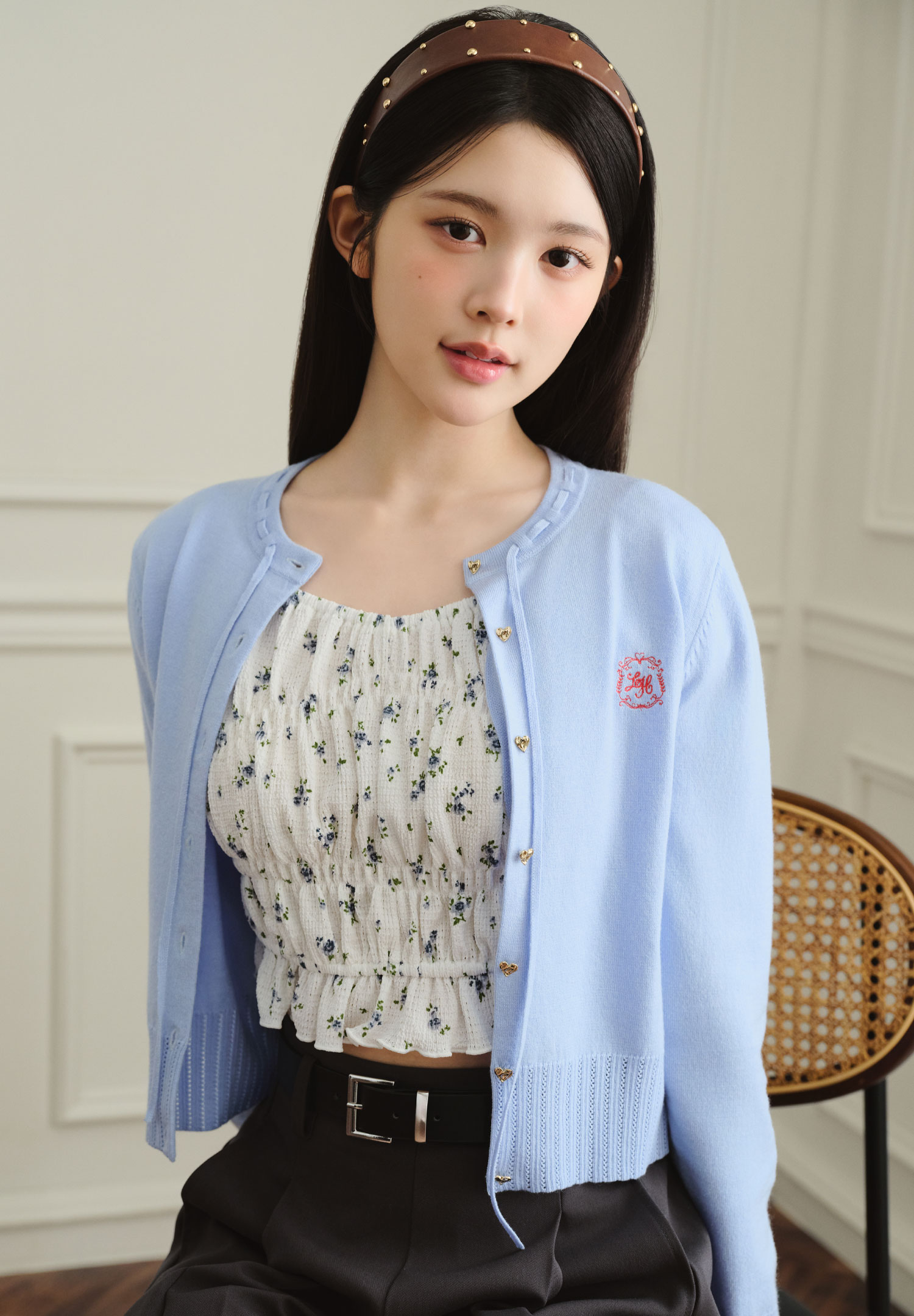 水色のカーディガンと花柄のインナーを着用した女性モデルの上半身カット