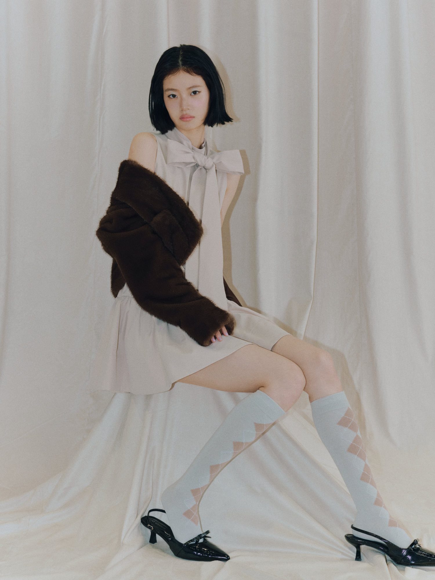 Fifteen Collection のメインビジュアル。ブラウンのエコファージャケットと白のドレスを着たモデル