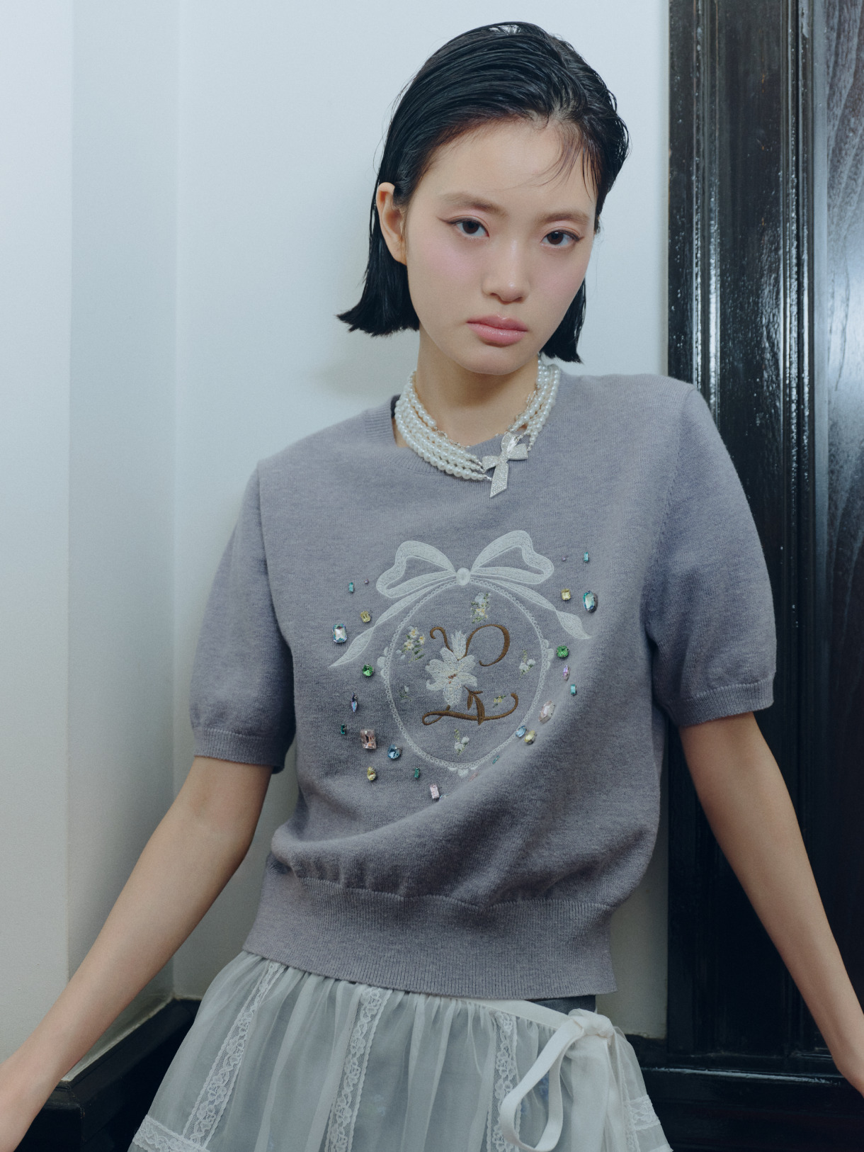 リボン刺繍のニットトップスとレースエプロンのアップ