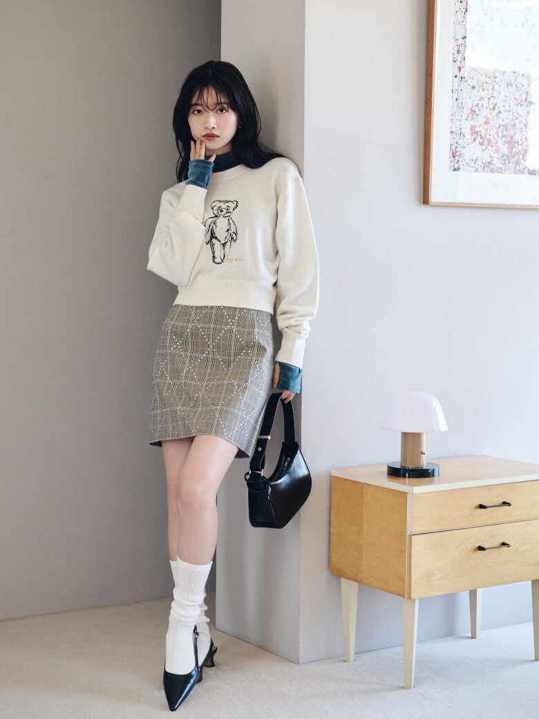 アイボリーのトップス・チェック柄のミニスカートを履いた女性