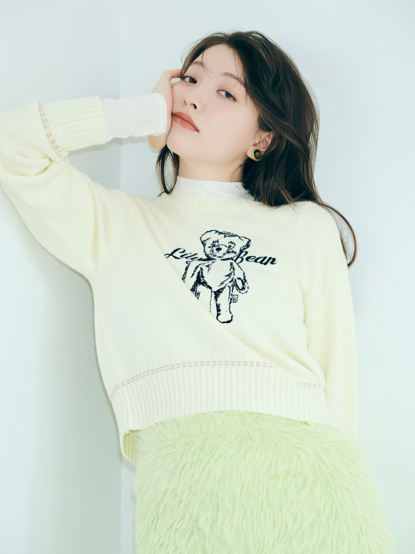 バリエーションオーバージャケット・Lily Bearエンブロイダリーニットトップス・ボウタイシアートップス・フェザーヤーンミニスカート・トゥレスシルキーハイソックス・リボンスリングバックパンプス・ヴィンテージモチーフイヤリングを着用した女性