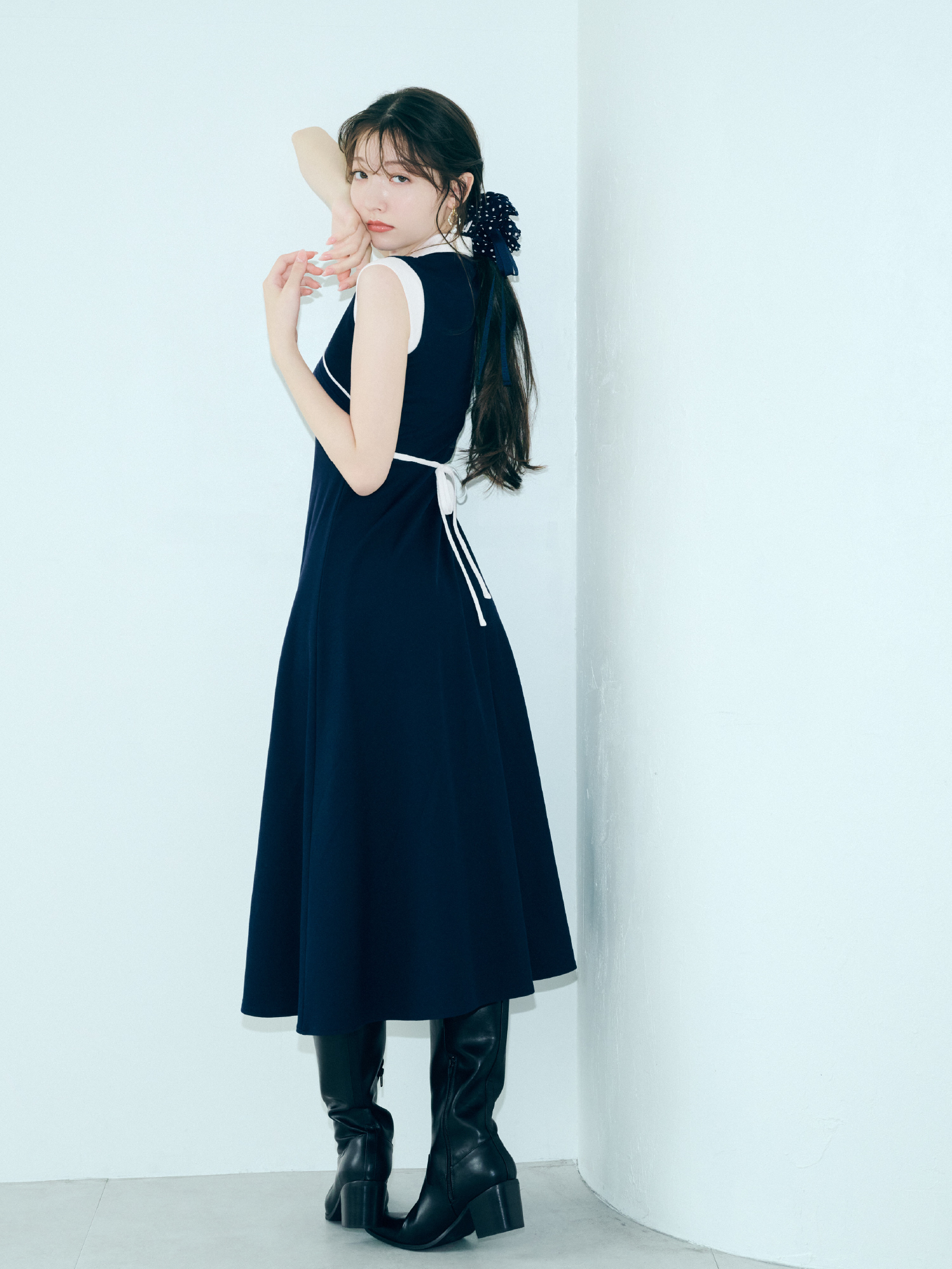 クロスカラーワンピース・LBビットフィットロングブーツ・バリエーションリボンシュシュを着用した女性
