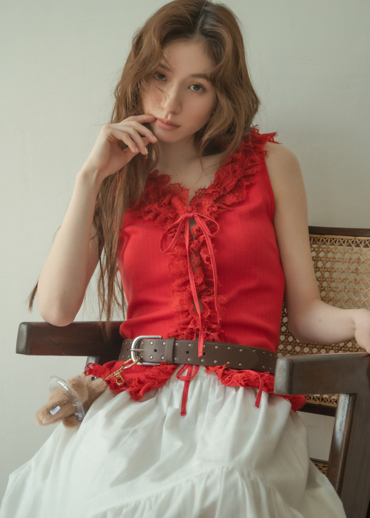 レッドのトップス・ホワイトのスカート・ブラウンのベルト・ブラウンのブーツを着用した女性