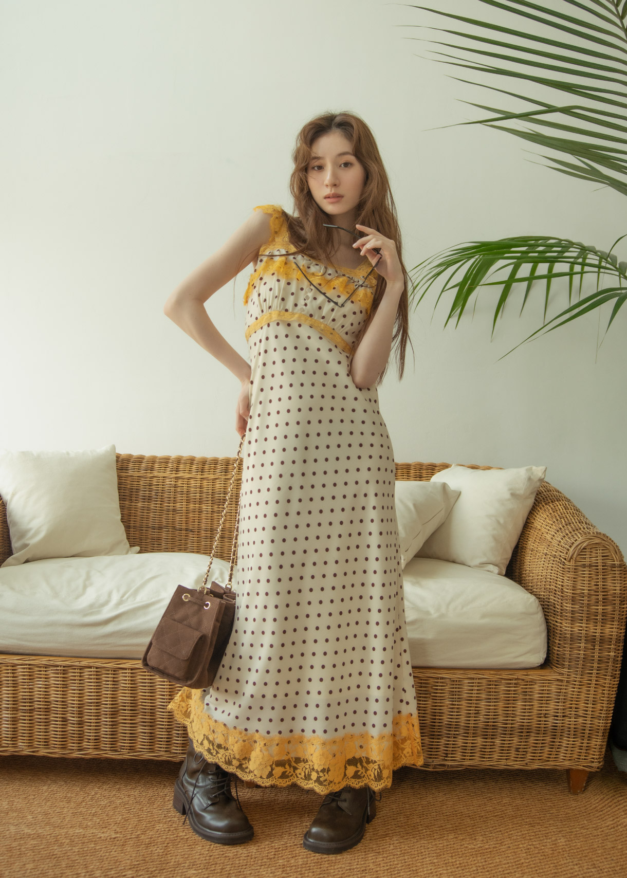 ホワイトとイエローとブラックのドットワンピース・ブラウンのブーツ・ブラウンのバッグを着用した女性