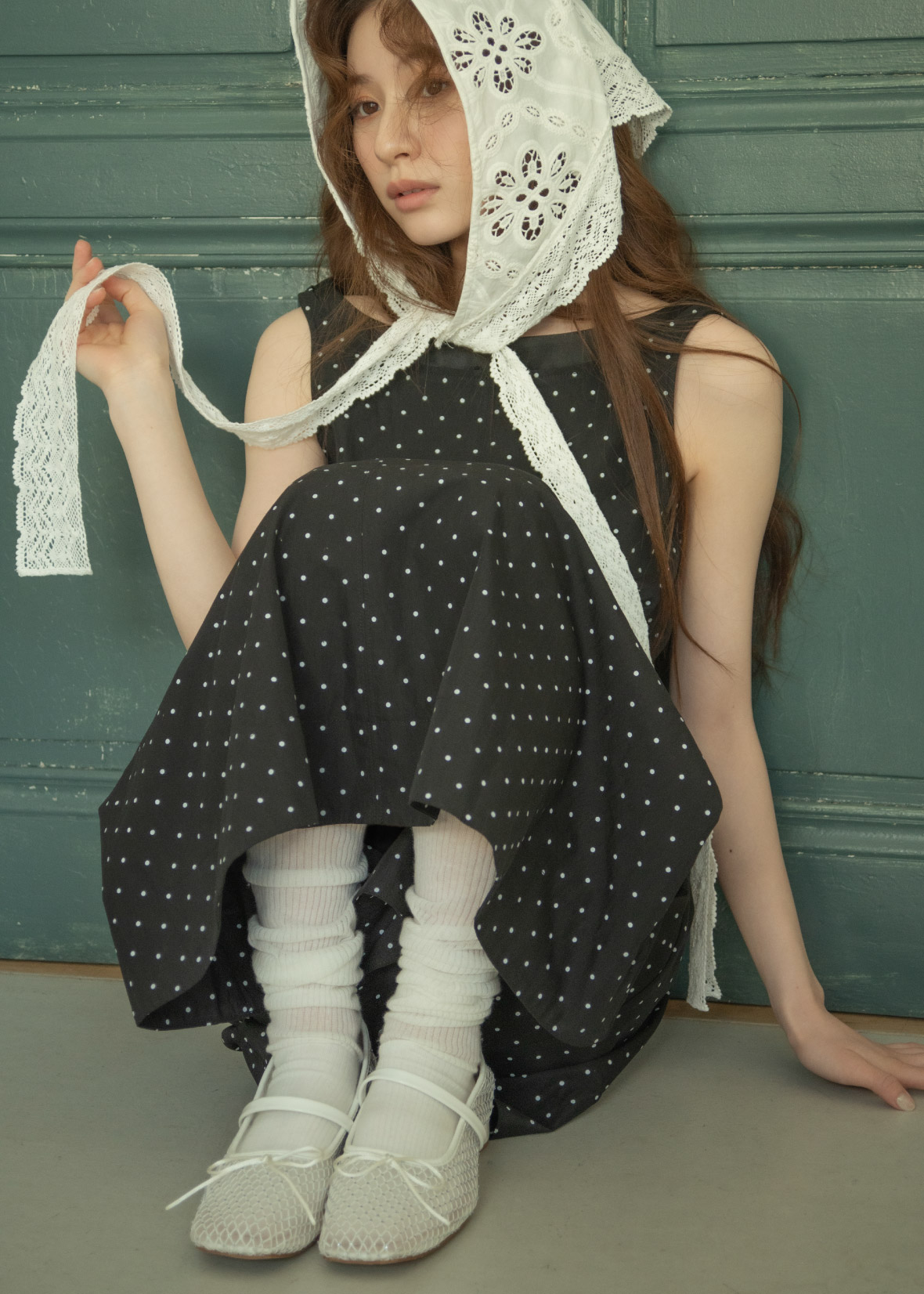 ホワイトのヘアアクセサリ・ブラックのドットワンピース・ホワイトのスニーカーを着用した女性