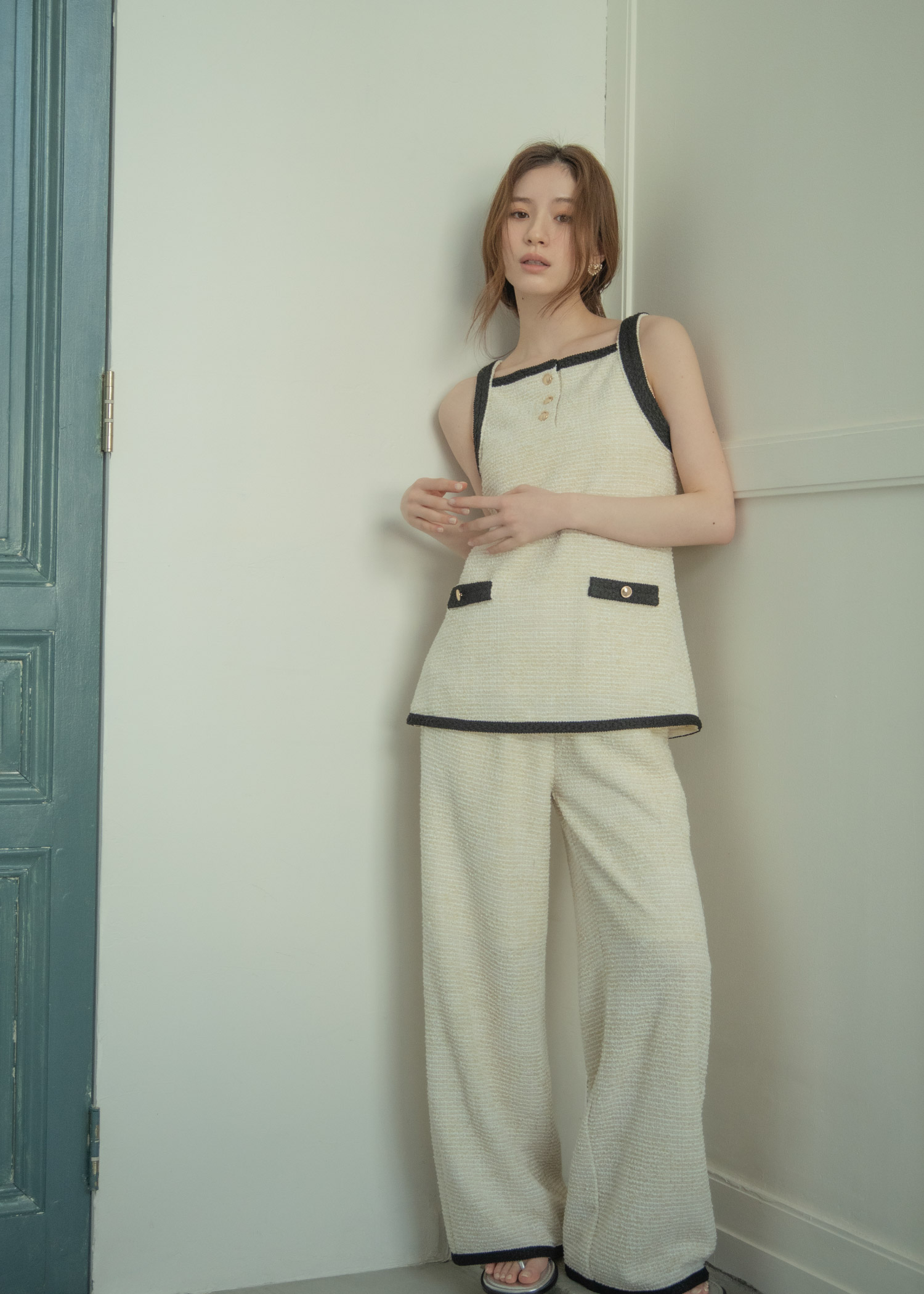 アイボリーのセットアップ・ブラックのサンダルを着用した女性