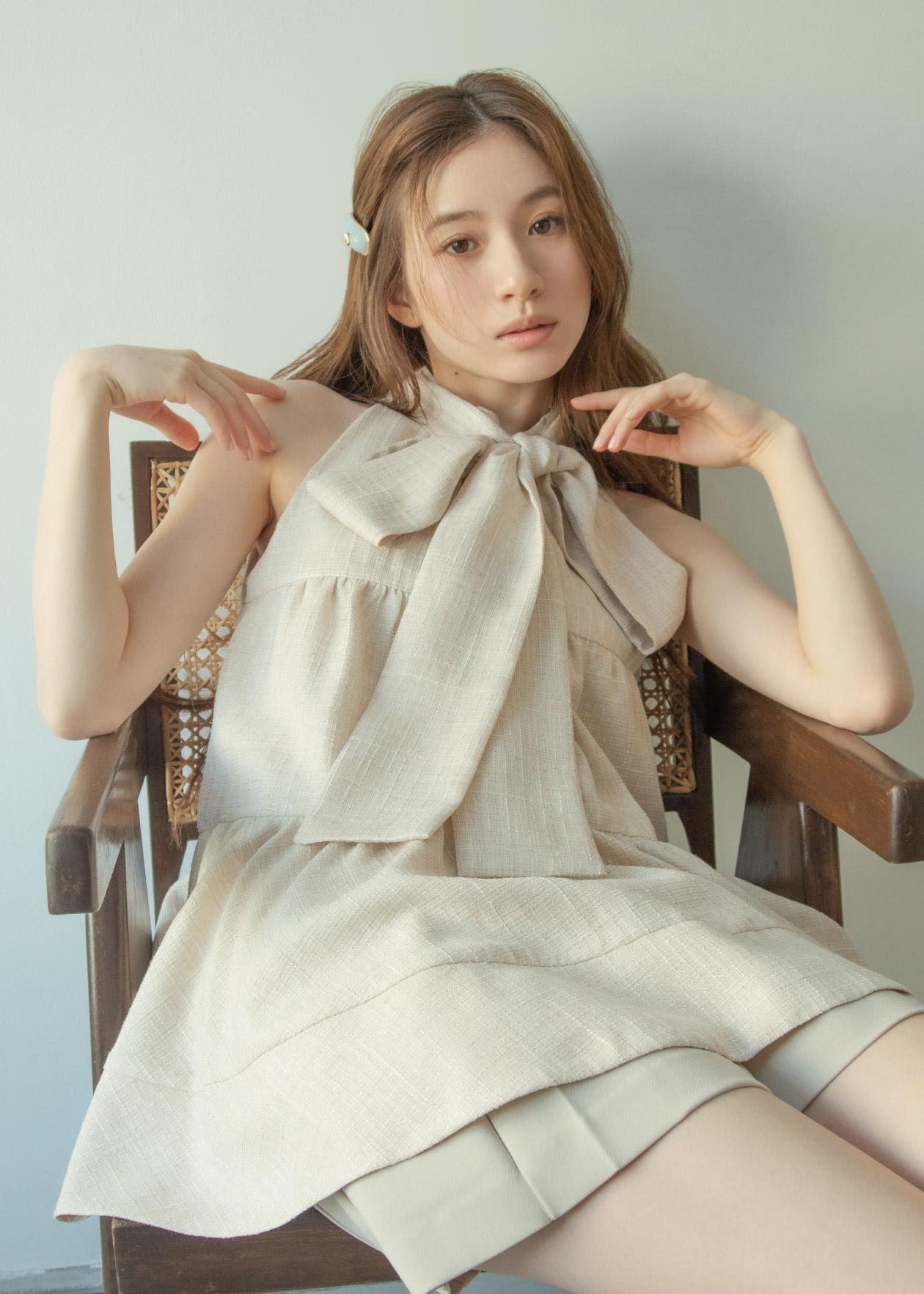 アイボリーのトップス・アイボリーのショートパンツ・ライトブルーのヘアアクセサリを着用した女性