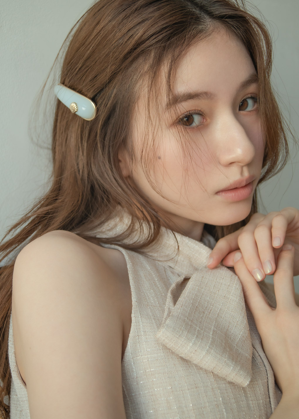 アイボリーのトップス・アイボリーのショートパンツ・ライトブルーのヘアアクセサリを着用した女性