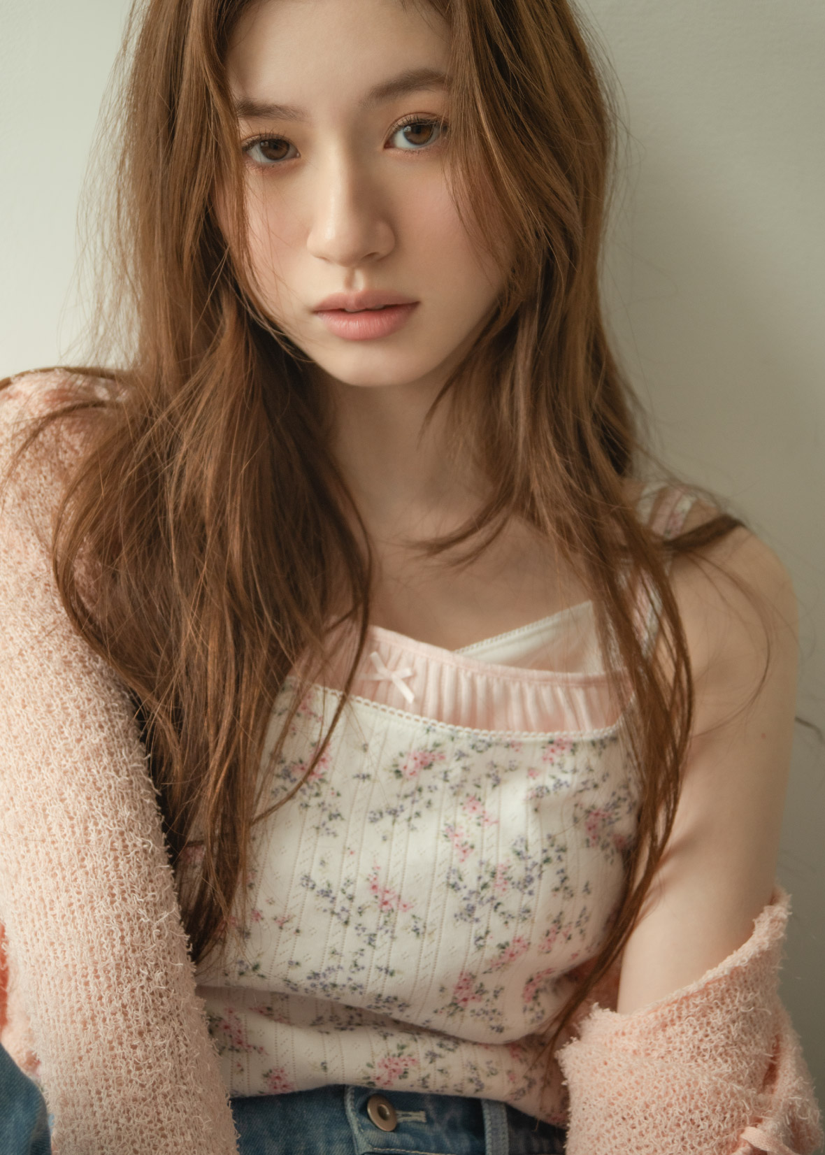 ライトピンクのカーディガン・花柄のトップス・ライトブルーのデニムパンツ・サンダルを着用した女性