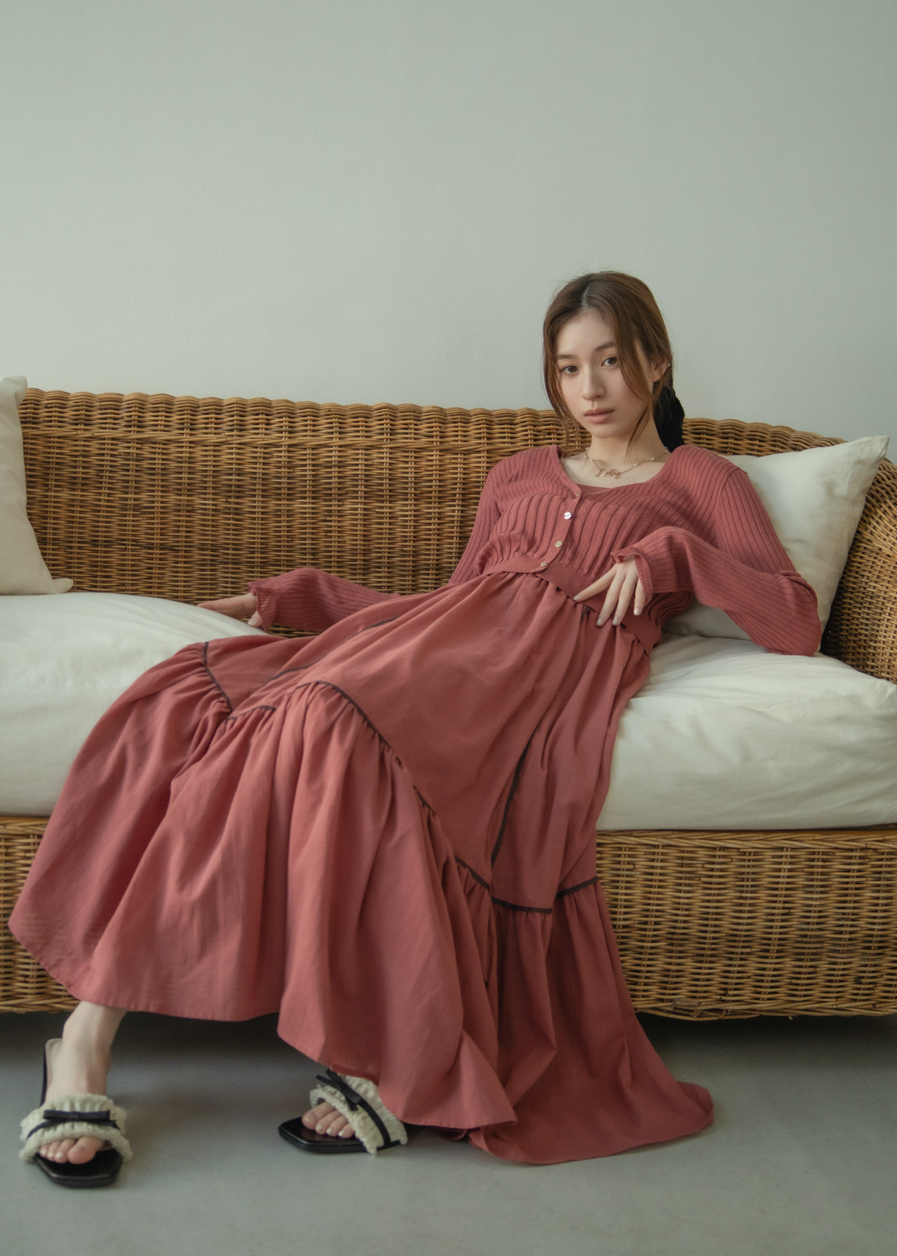 くすんだピンクのカーディガン・ドレス・ヘアアクセサリ・ネックレスを着用した女性