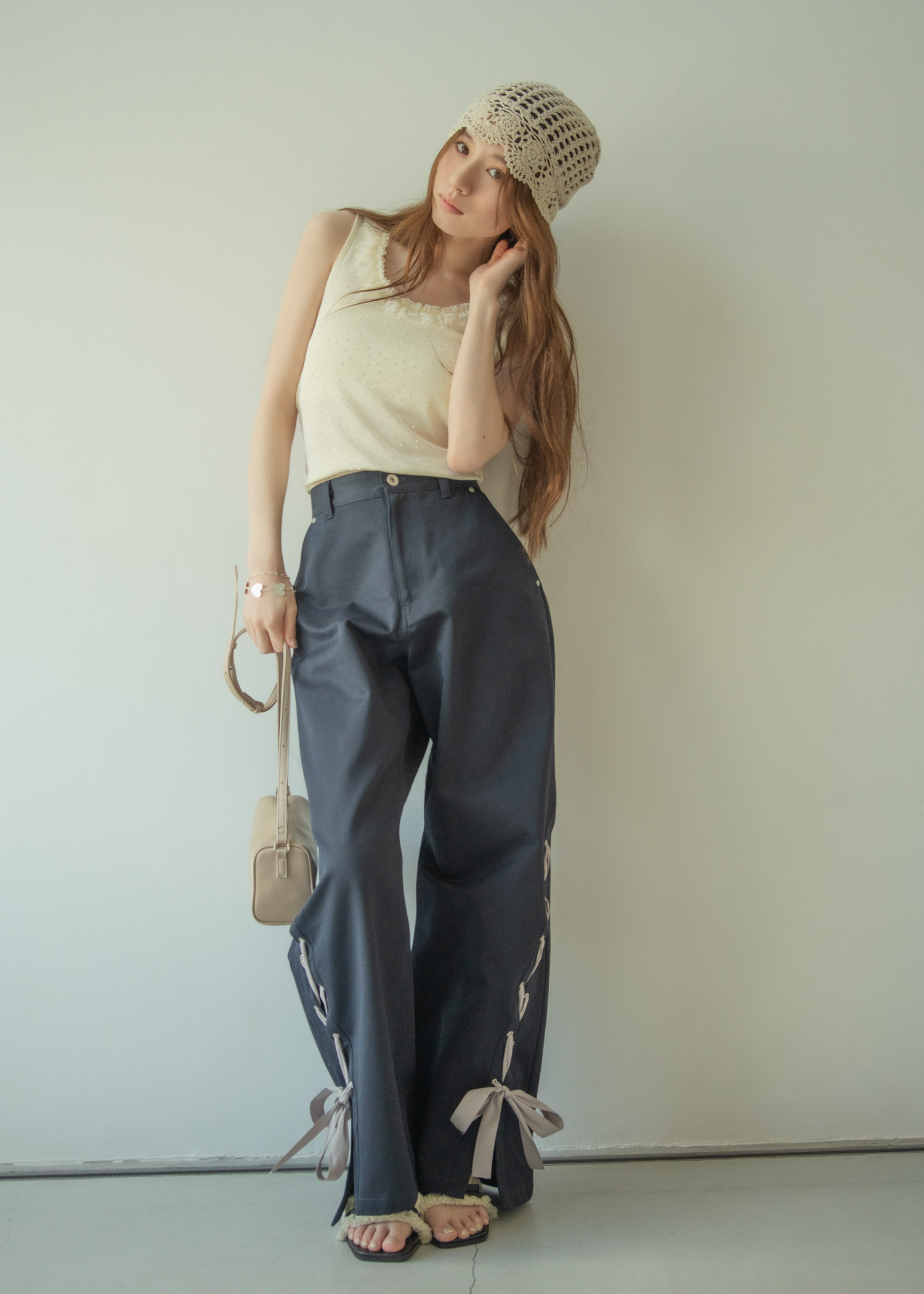 ニットキャップ、ドット柄のタンクトップ、リボン付きのワイドパンツを合わせた女性のコーディネート。