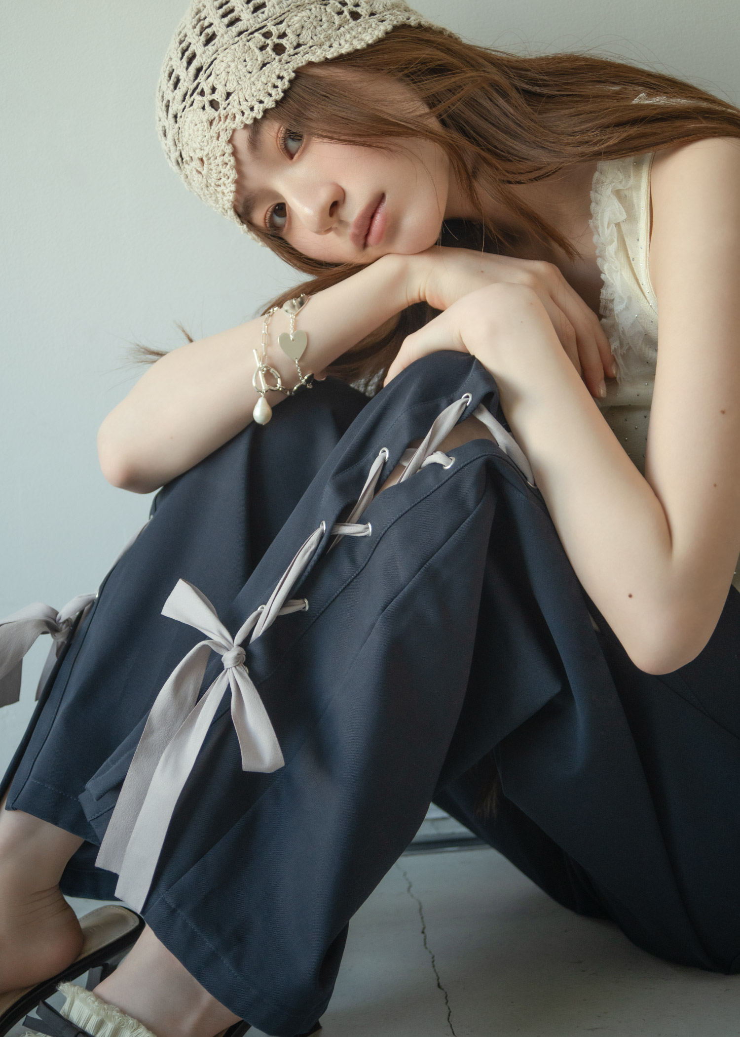 ニットキャップ、ドット柄のタンクトップ、リボン付きのワイドパンツを合わせた女性のコーディネート。